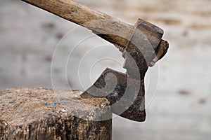 Old rusty axe stuck in the stump