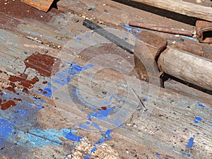 An old rusty axe with a wooden handle is stuck in the slot of a wooden work table.