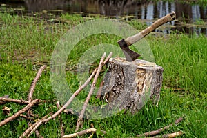 Old rusty axe with wooden handle stuck in the stump. blurred background with pile of wood logs, Large ax sticks out in