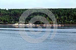 Old rusty barge sailing along the river, carrying huge piles of rubble from quarry