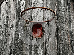 Old rusty basketball hoop mounted on a wooden wall of a barn of a farm. Popular sport. Practice and develop skill in tough rough