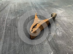 old rusty battery clip, unused on a gray background in the barn