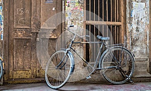 Old rusty bicycle at the doorway of a weathered house