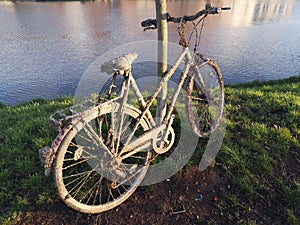 Old rusty bike was pulled out of the water. It lay in water for a long time and is covered with mud and shells.