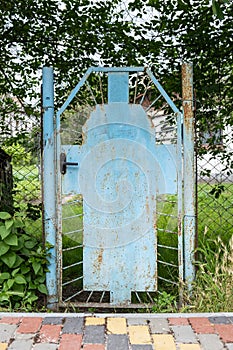 An old rusty blue metal gate in front of the apartment building