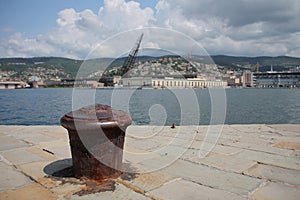 Old rusty bollard on pier in Trieste, Italy