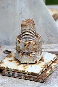 Old rusty bolt with two nuts in two-layered metal plate