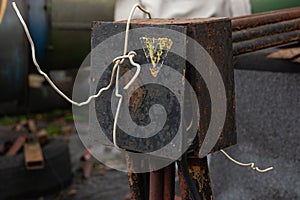 An old, rusty box for connecting wires and cables is full of wires. the lid of the box is tied with a wire.