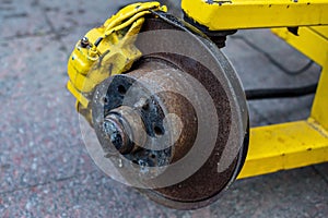 Old rusty brake disc on a yellow trailer frame