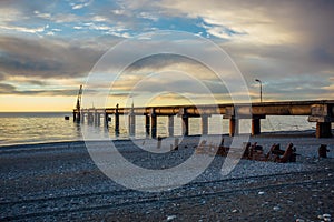 Old rusty broken abandoned pier on sunset background