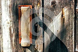 Old rusty broken door handle on wooden door of old barn. Toned.