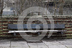 Old rusty broken park bench on red brick wall background