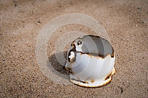 An old rusty broken pot lying on a sandy beach