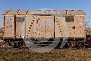 Old rusty brown train wagon on abandoned tracks