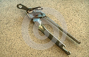 An old rusty can opener on the tile table