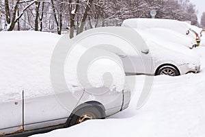 Old rusty car covered snow. Many cars on parking under snow in snowbank after snowfall