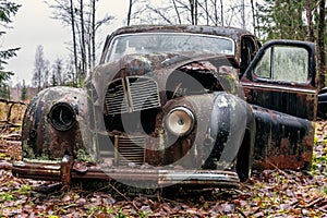 Old rusty car wreck standing in the forest