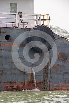 Old and rusty cargo ship side view. Old waterway vessel and tanker ship on a river. Ship with tire and rusty metal body going
