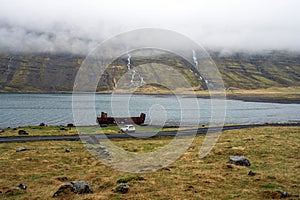 Old and rusty cargo ship wreckage laying on the fjord bank in Mjoifjordur in east Iceland