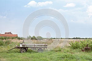 Old and rusty cart, empty, standing  next to a field during a cloudy afternoon in Uljma, a small Serbian village of Vojvodina