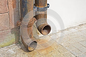 Old rusty cast iron downpipe against a wall