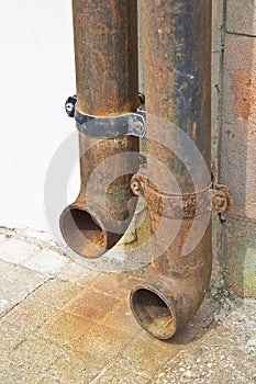 Old rusty cast iron downpipe against a wall