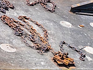 Old rusty chain attached to metal dock along harbor