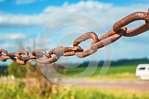 Old rusty chain on the field on the background of the sky