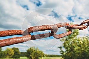 Old rusty chain on the field on the background of the sky