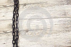 Old rusty chain lays on wooden background.