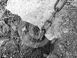 An old, rusty chain leads into the pit. An old chain hangs. black and white photo. Life-threatening.