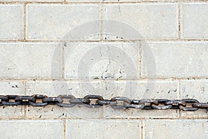 Old rusty chain lies on a flat white tile