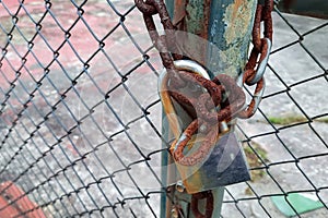 Old rusty chain with metal padlock hanging on the fence