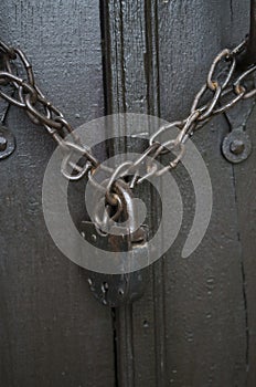 Old rusty chain with a padlock on wooden door close