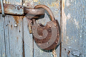 Old rusty closed lock without key. Vintage wooden door, close up concept photo