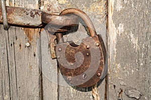 Old rusty closed lock without key. Vintage wooden door, close up concept photo