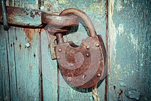 Old rusty closed lock without key. Vintage wooden door, close up concept photo