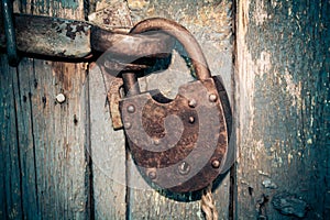 Old rusty closed lock without key. Vintage wooden door, close up concept photo