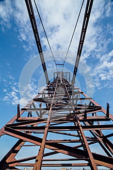 Old rusty crane arrow on blue sky background