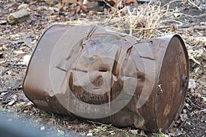 old rusty crumpled metal barrel lies on the ground