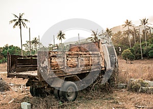 Old rusty destroy car standing in rural tropic place at sunset