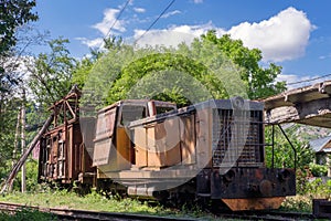 Old rusty diesel locomotive with broken wooden cargo wagon