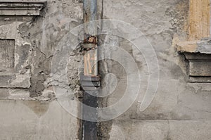 Old rusty drainpipe and deteriorated house wall