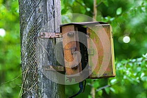 An old rusty electrical junction box on a wooden pole
