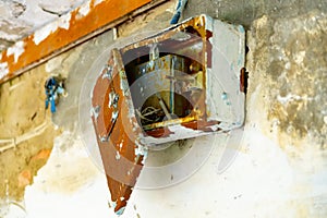 An old rusty electrical panel on the wall of the house. a panel on the white brick wall of an old house