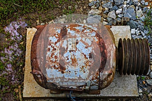 Old rusty engine parts surrounded by rocks and lush green grass and plants at Vickery Creek