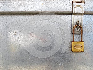 old rusty golden padlock with blank sign hanging with metallic hinge for lock on aluminum chest box cover