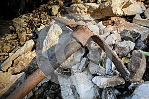 Old rusty hack axe on the heap of rocks in the garden