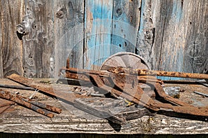 An old rusty hand saw and other metal objects on a wooden shelf