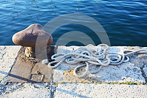 Old rusty harbor on boat pier with sea rope in Pula.